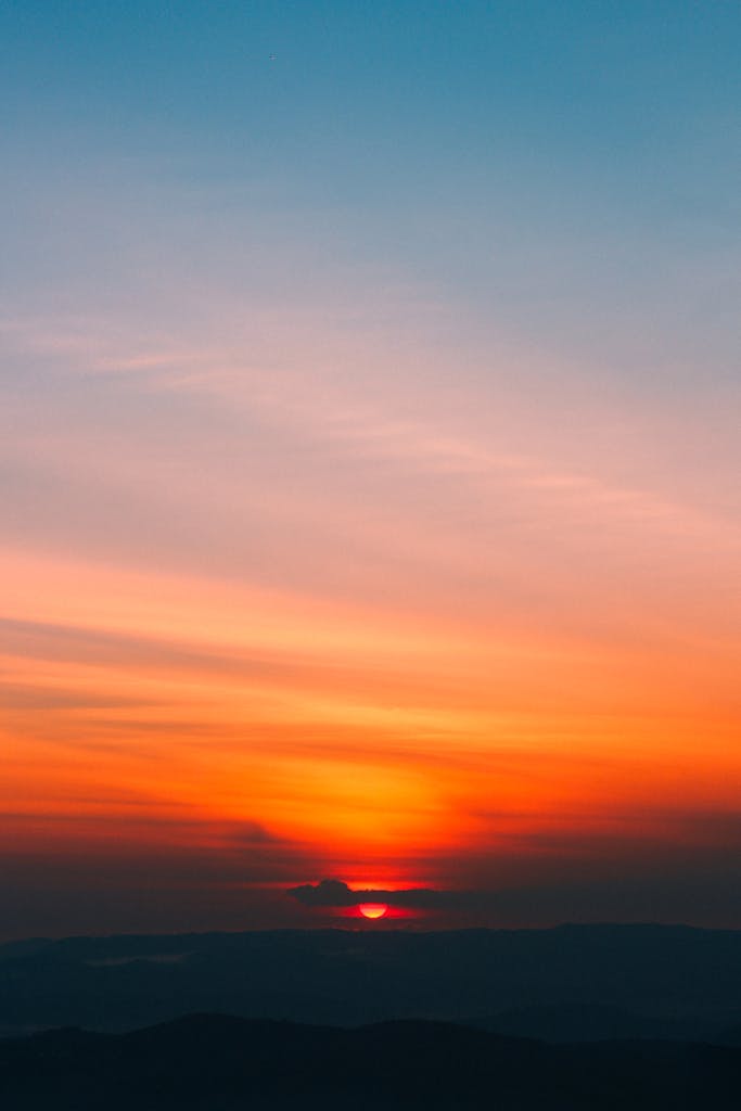 Dramatic sunrise with vibrant orange and blue hues painting the sky, creating a serene and peaceful scene.