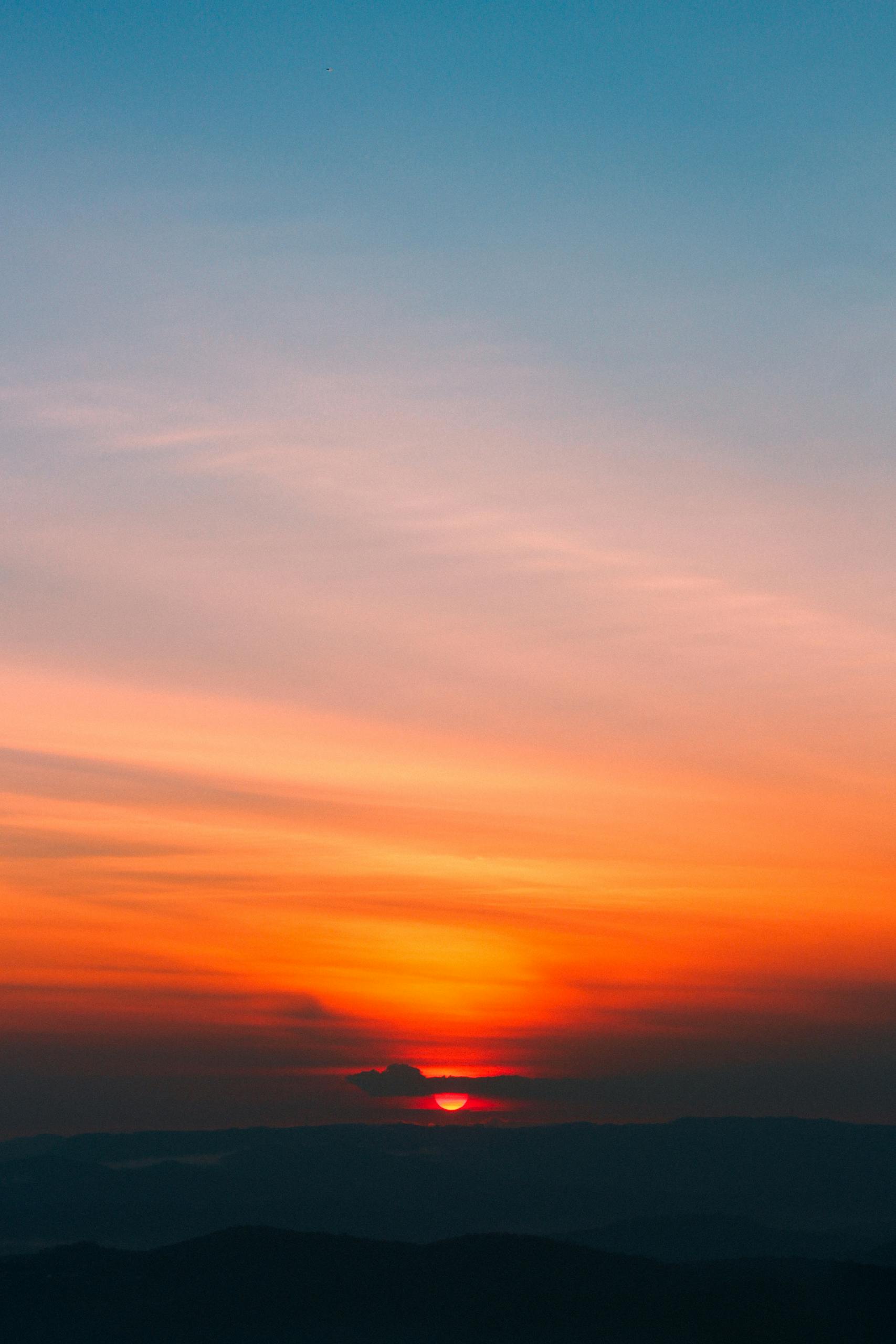 Dramatic sunrise with vibrant orange and blue hues painting the sky, creating a serene and peaceful scene.